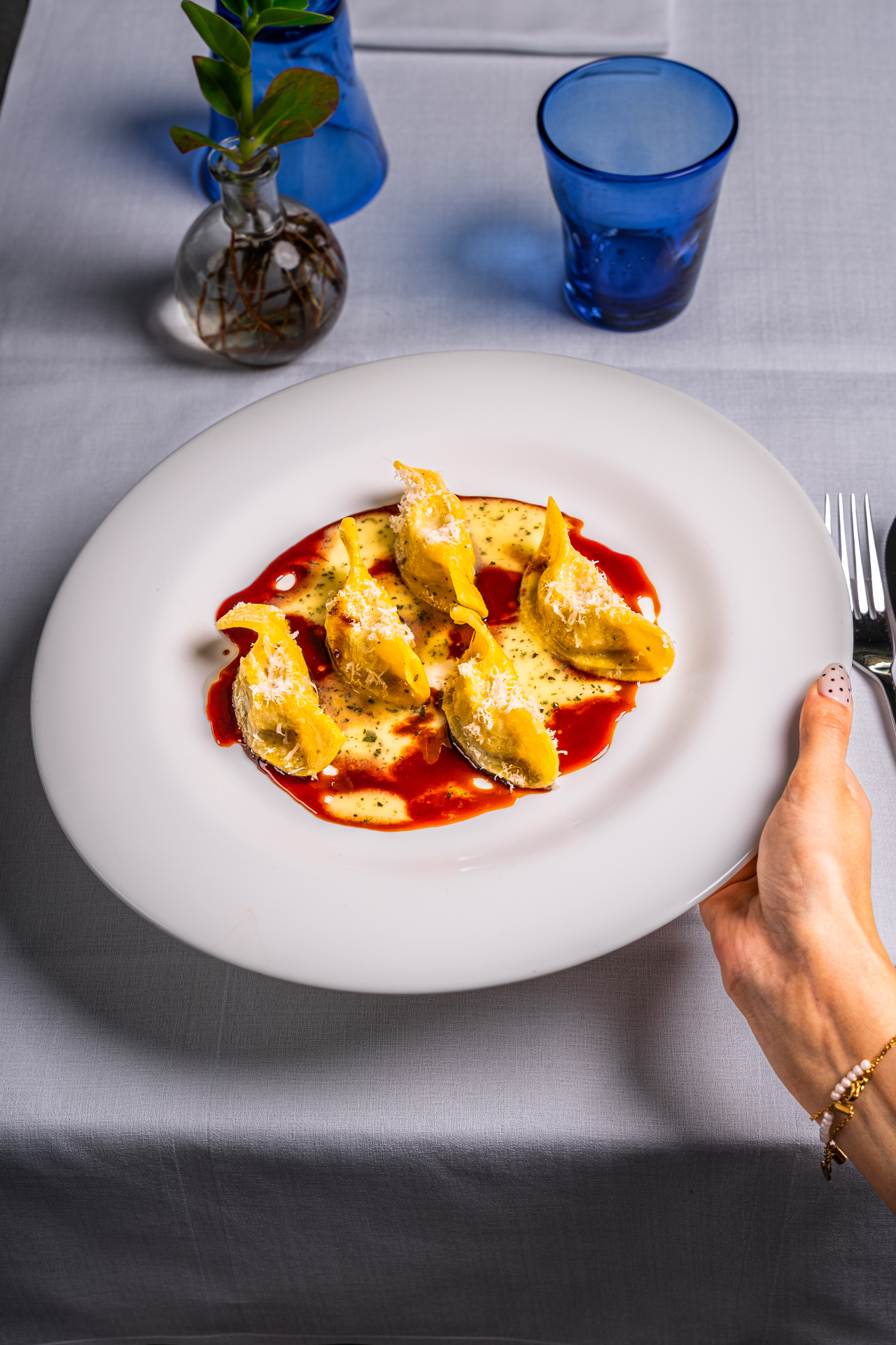 Casoncelli serviti al tavolo con bicchiere blu — fotografo culinario Mantova